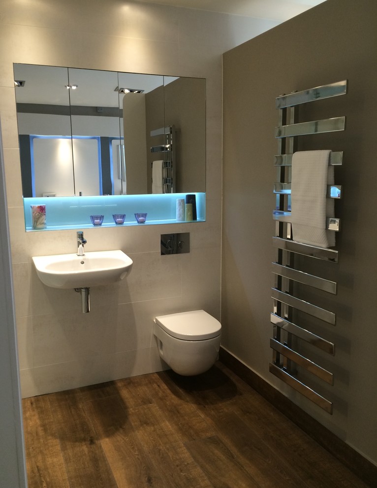 Design ideas for a modern bathroom in Dublin with a wall-mounted sink, glass-front cabinets, glass worktops, an alcove shower, a wall mounted toilet, beige tiles, ceramic tiles, beige walls and ceramic flooring.
