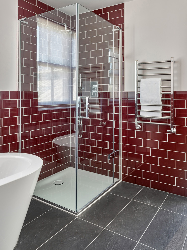 Modelo de cuarto de baño infantil actual de tamaño medio con bañera exenta, ducha abierta, baldosas y/o azulejos rojos y suelo de pizarra