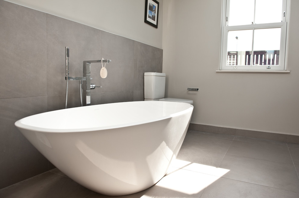Photo of a large contemporary family bathroom in London with flat-panel cabinets, dark wood cabinets, a freestanding bath, a corner shower, a one-piece toilet, grey tiles, ceramic tiles, white walls, ceramic flooring and a wall-mounted sink.