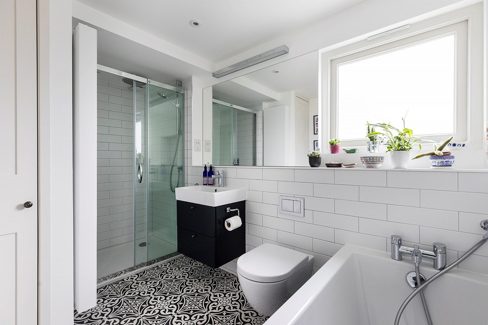 Modern inredning av ett mellanstort badrum, med släta luckor, svarta skåp, en öppen dusch, en vägghängd toalettstol, vit kakel, tunnelbanekakel, vita väggar, cementgolv, ett väggmonterat handfat, flerfärgat golv och dusch med skjutdörr