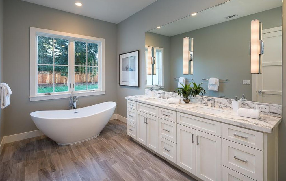 Medium sized rural shower room bathroom in San Francisco with shaker cabinets, white cabinets, a freestanding bath, grey walls, medium hardwood flooring, a submerged sink, marble worktops and brown floors.