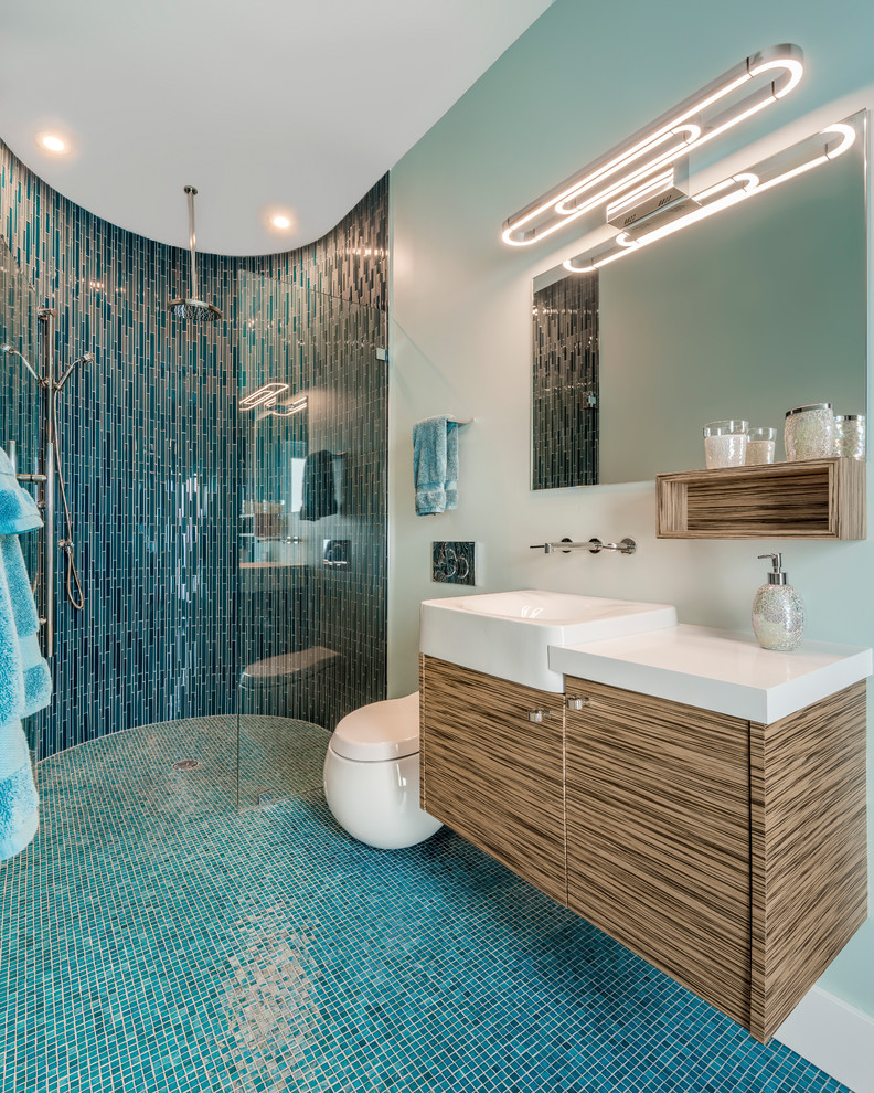 Example of a mid-sized trendy blue tile and glass tile beige floor and mosaic tile floor bathroom design in Miami with flat-panel cabinets, brown cabinets, a wall-mount toilet, blue walls, a wall-mount sink, quartz countertops, a hinged shower door and white countertops