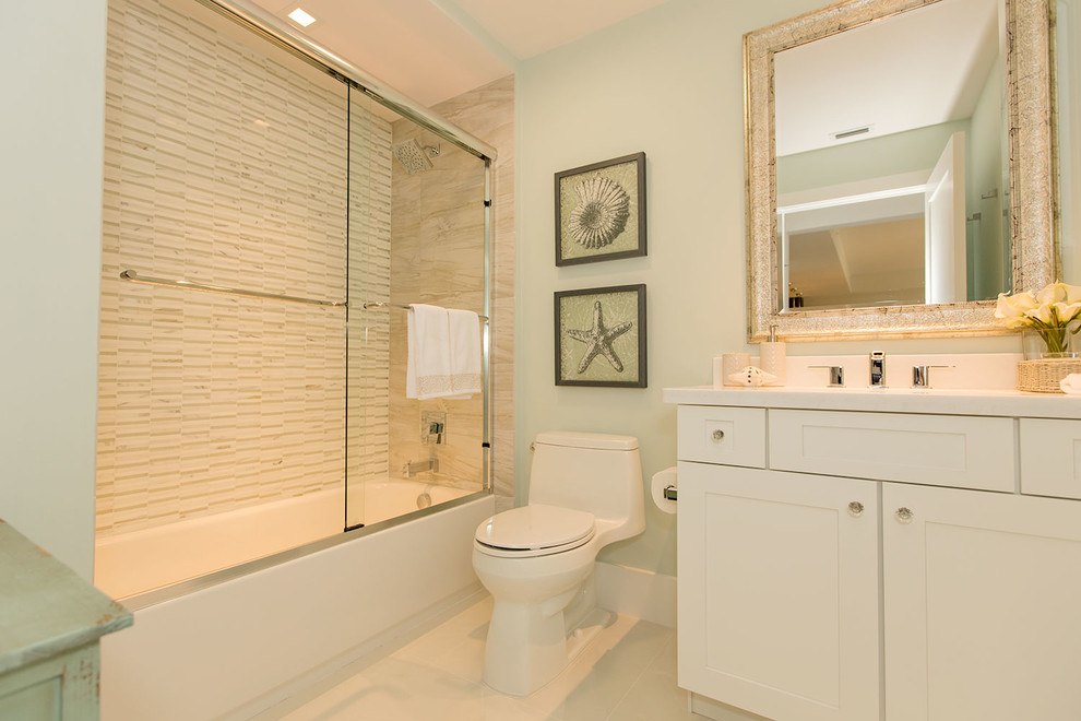 Example of a mid-sized beach style white tile and porcelain tile porcelain tile bathroom design in Miami with recessed-panel cabinets, white cabinets, a one-piece toilet, blue walls, an integrated sink and granite countertops