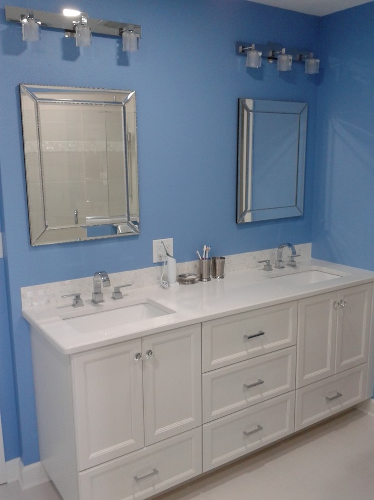 Modelo de cuarto de baño tradicional renovado con lavabo bajoencimera, armarios con paneles lisos, puertas de armario blancas, encimera de granito y paredes azules