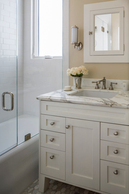 This is an example of a medium sized traditional ensuite bathroom in San Francisco with shaker cabinets, white cabinets, an alcove bath, metro tiles, beige walls, a submerged sink, marble worktops, an alcove shower, white tiles, mosaic tile flooring, white floors and a shower curtain.