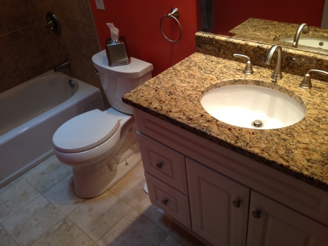 Photo of a medium sized traditional family bathroom in Cleveland with raised-panel cabinets, white cabinets, an alcove bath, an alcove shower, a two-piece toilet, beige tiles, porcelain tiles, multi-coloured walls, porcelain flooring, a submerged sink and granite worktops.