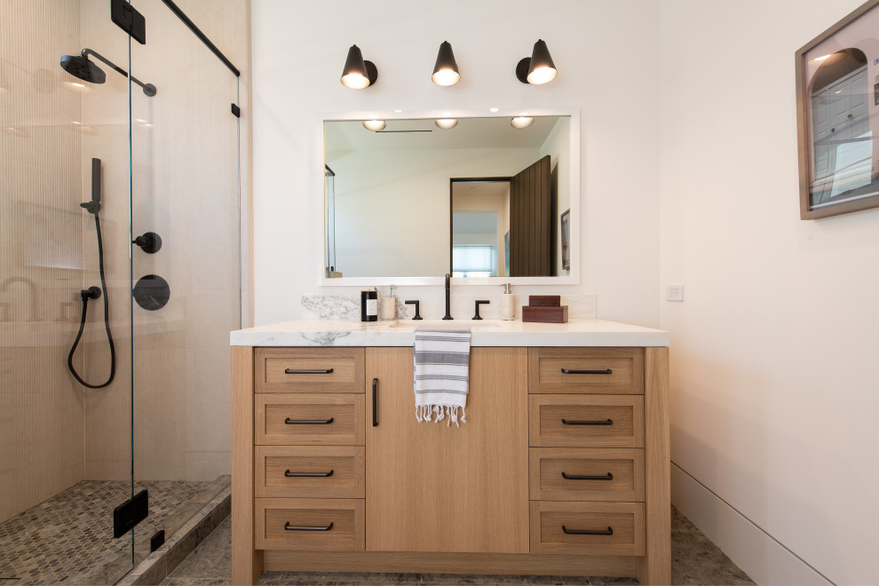 Photo of a medium sized traditional bathroom in Orange County with recessed-panel cabinets, light wood cabinets, an alcove shower, a one-piece toilet, grey tiles, marble tiles, white walls, vinyl flooring, a submerged sink, limestone worktops, grey floors, a hinged door, beige worktops, a single sink and a floating vanity unit.