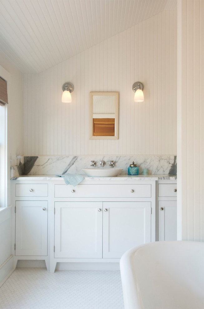 Imagen de cuarto de baño costero con lavabo sobreencimera, armarios estilo shaker, puertas de armario blancas, paredes blancas y suelo con mosaicos de baldosas
