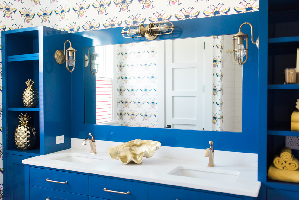 Cette image montre une salle de bain marine pour enfant avec un placard à porte plane, des portes de placard bleues, un mur multicolore, un lavabo encastré et un plan de toilette blanc.