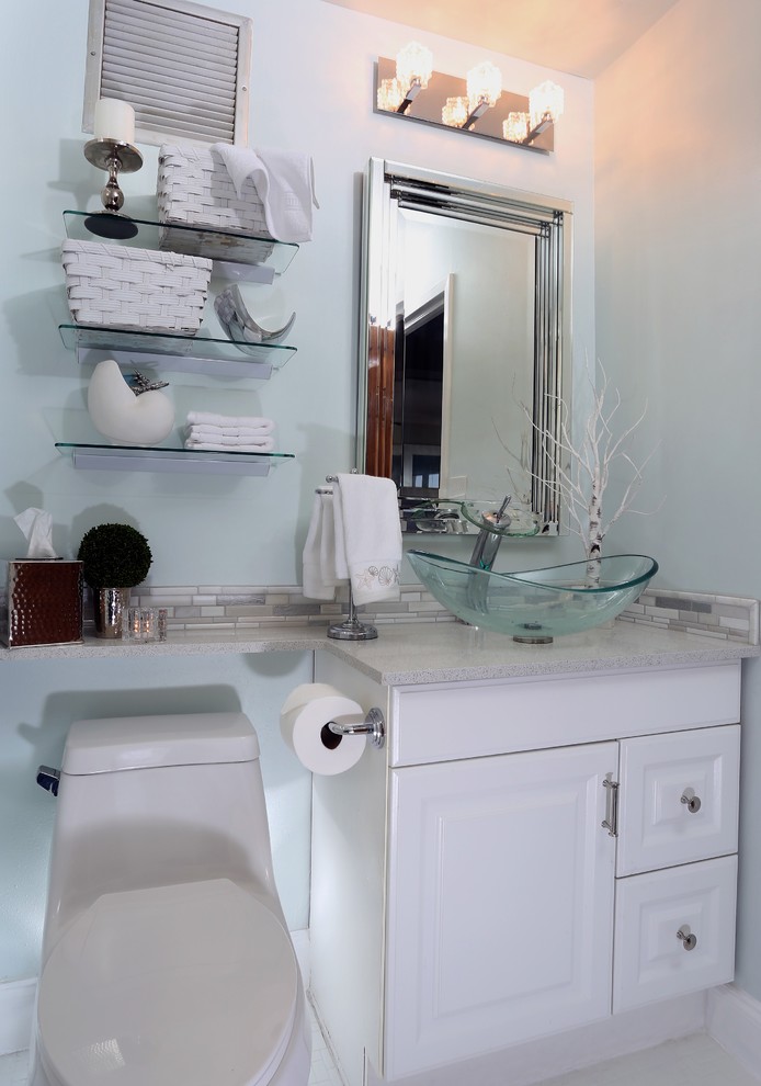 This is an example of a medium sized beach style shower room bathroom in Miami with recessed-panel cabinets, white cabinets, an alcove bath, a shower/bath combination, a one-piece toilet, grey tiles, matchstick tiles, blue walls, mosaic tile flooring, a vessel sink, laminate worktops, white floors and a sliding door.