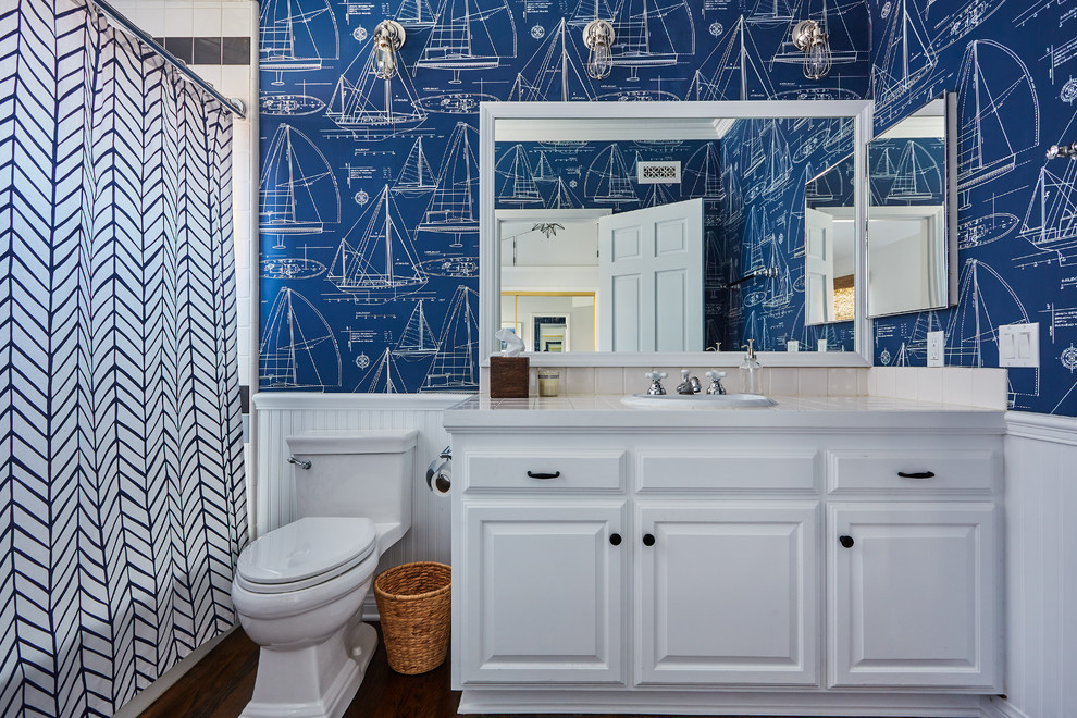 Inspiration för ett mellanstort vintage badrum för barn, med luckor med upphöjd panel, vita skåp, en dusch/badkar-kombination, blå väggar, mellanmörkt trägolv, ett nedsänkt handfat, kaklad bänkskiva, beige kakel och dusch med duschdraperi