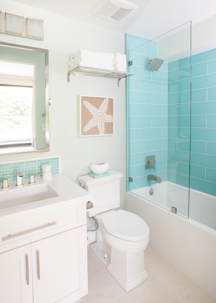 Immagine di una stanza da bagno stile marinaro con lavabo sottopiano, ante in stile shaker, ante bianche, vasca ad alcova, vasca/doccia, WC a due pezzi, piastrelle blu, piastrelle di vetro e pareti bianche