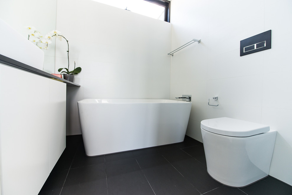 Photo of a small contemporary shower room bathroom in Melbourne with flat-panel cabinets, white cabinets, a freestanding bath, an alcove shower, a two-piece toilet, black and white tiles, porcelain tiles, a console sink and engineered stone worktops.