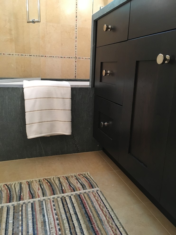 Пример оригинального дизайна: маленькая детская ванная комната в стиле неоклассика (современная классика) с фасадами с утопленной филенкой, темными деревянными фасадами, полновстраиваемой ванной, душем над ванной, желтой плиткой, плиткой из известняка, бежевыми стенами, полом из мозаичной плитки, врезной раковиной, столешницей из талькохлорита, разноцветным полом и душем с распашными дверями для на участке и в саду