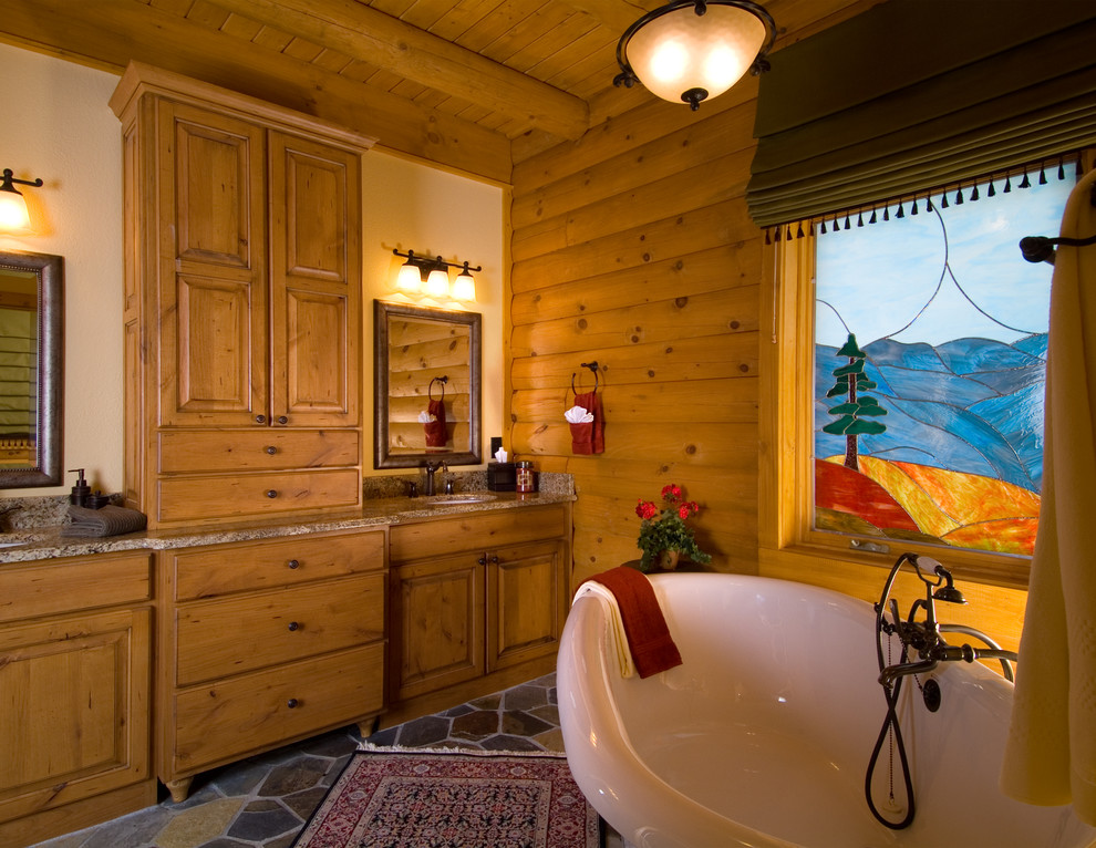 Foto på ett mellanstort rustikt en-suite badrum, med luckor med upphöjd panel, skåp i mellenmörkt trä, ett badkar med tassar, en toalettstol med separat cisternkåpa, beige väggar, skiffergolv, ett undermonterad handfat och granitbänkskiva