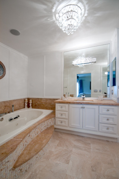 Exemple d'une salle de bain principale bord de mer de taille moyenne avec un placard avec porte à panneau encastré, des portes de placard blanches, un plan de toilette en marbre, un carrelage beige et un carrelage de pierre.