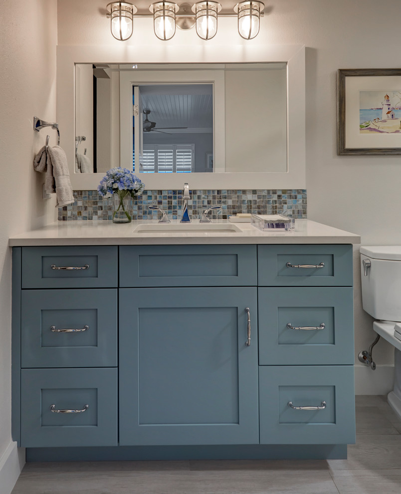 Foto på ett litet maritimt beige en-suite badrum, med skåp i shakerstil, blå skåp, en dusch i en alkov, en toalettstol med separat cisternkåpa, beige kakel, beige väggar, klinkergolv i porslin, ett undermonterad handfat, bänkskiva i kvarts, grått golv och med dusch som är öppen