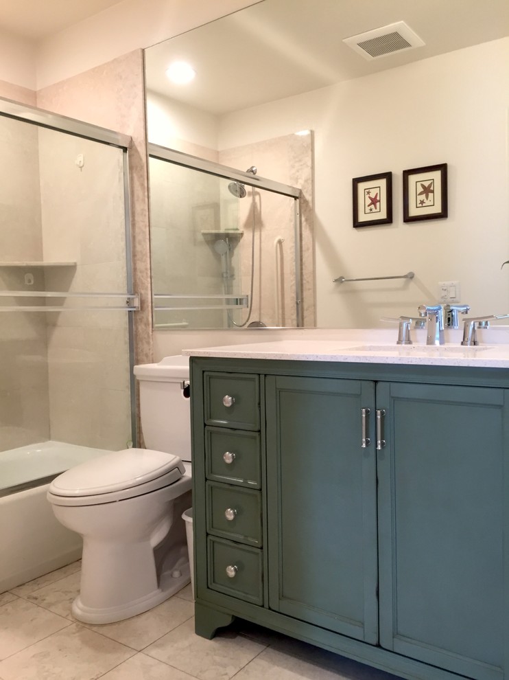 Inspiration for a medium sized coastal ensuite bathroom in Santa Barbara with recessed-panel cabinets, green cabinets, a built-in bath, a shower/bath combination, a two-piece toilet, beige tiles, stone slabs, white walls, marble flooring, a submerged sink and marble worktops.