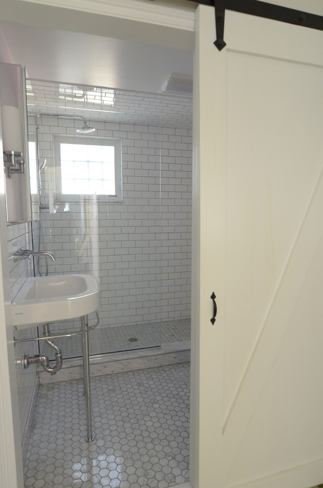 Maritim inredning av ett litet badrum, med ett väggmonterat handfat, marmorbänkskiva, en dusch i en alkov, en toalettstol med separat cisternkåpa, vit kakel, keramikplattor, marmorgolv och vita väggar