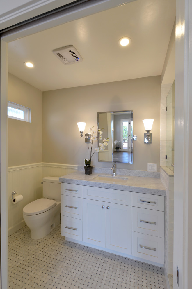Foto på ett litet maritimt en-suite badrum, med skåp i shakerstil, vita skåp, en dusch i en alkov, en toalettstol med hel cisternkåpa, grå kakel, tunnelbanekakel, vita väggar, mosaikgolv, ett undermonterad handfat och marmorbänkskiva