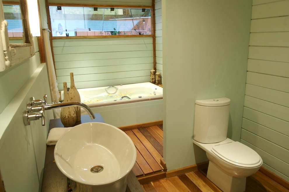 Diseño de cuarto de baño tropical con lavabo tipo consola y ventanas