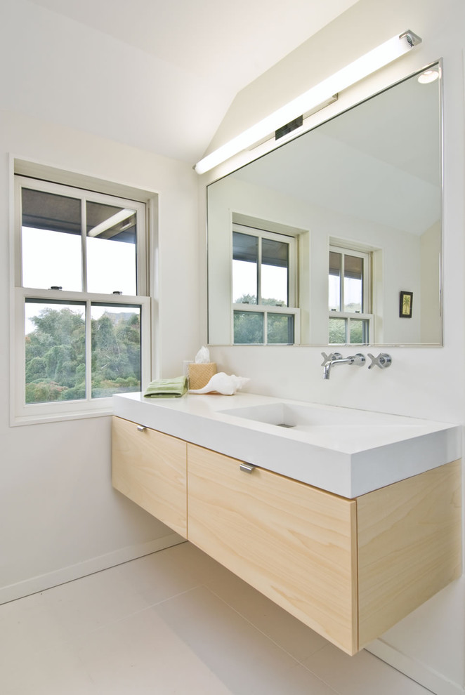 Esempio di una stanza da bagno minimal con lavabo integrato, ante lisce e ante in legno chiaro