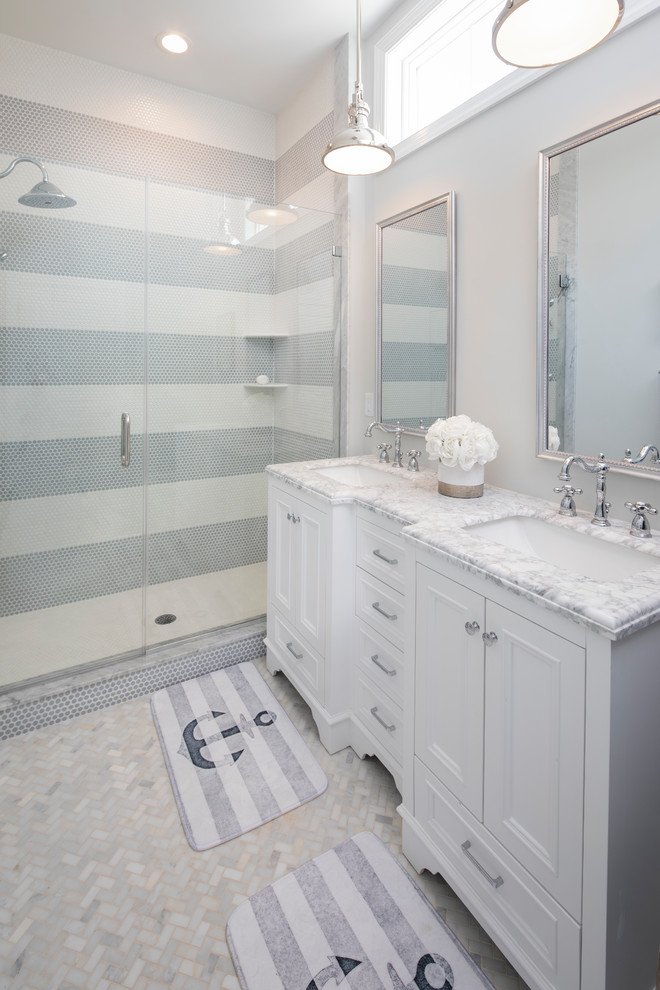Inredning av ett maritimt grå grått en-suite badrum, med vita skåp, vit kakel, grå kakel, dusch med gångjärnsdörr, luckor med infälld panel, en dusch i en alkov, mosaik, grå väggar, ett undermonterad handfat och grått golv