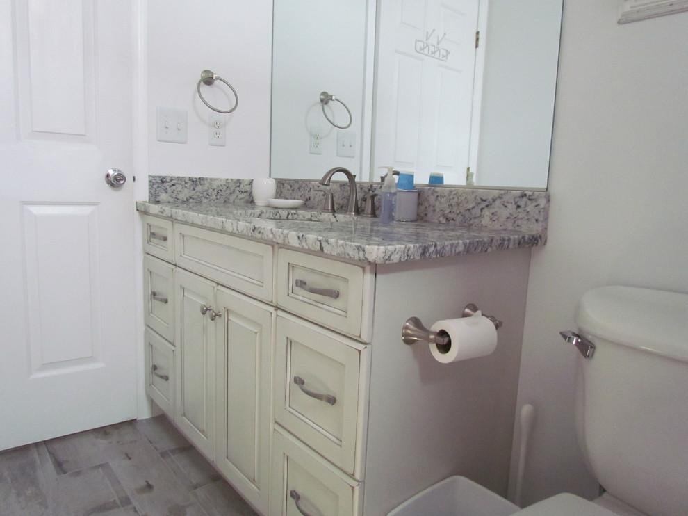 Exempel på ett mellanstort klassiskt badrum, med ett undermonterad handfat, luckor med upphöjd panel, skåp i slitet trä, granitbänkskiva, ett badkar i en alkov, en dusch/badkar-kombination, en toalettstol med separat cisternkåpa, grå väggar och klinkergolv i porslin