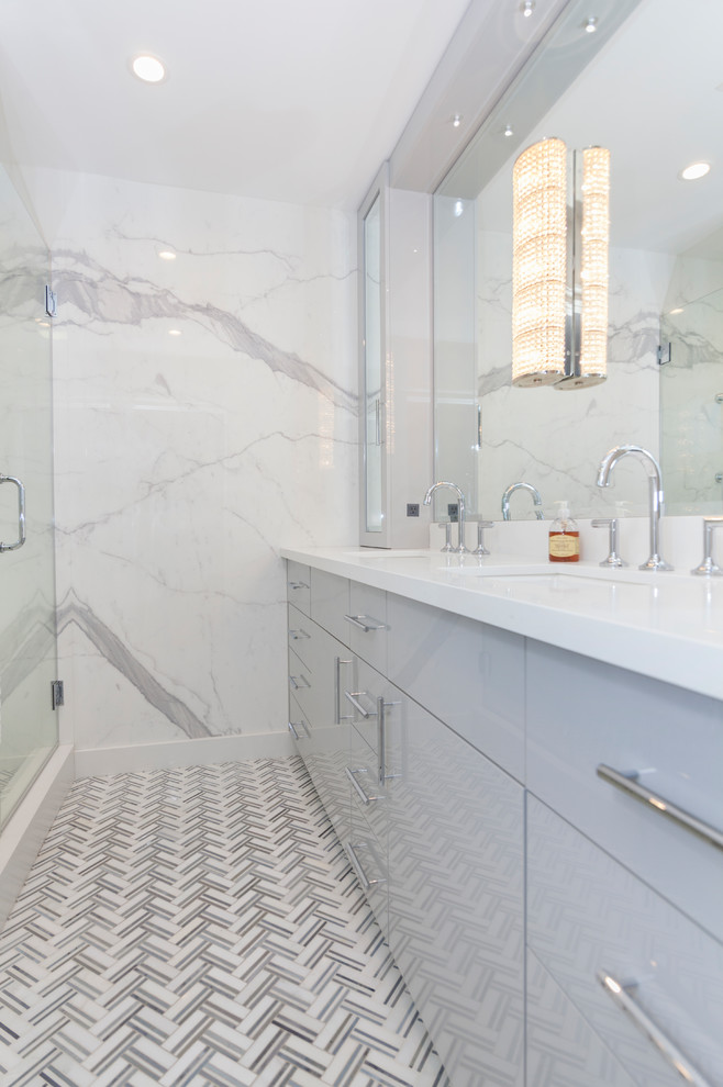 Alcove shower - mid-sized coastal 3/4 gray tile and marble tile ceramic tile and white floor alcove shower idea in Huntington with flat-panel cabinets, gray cabinets, gray walls, an undermount sink, solid surface countertops, a hinged shower door and white countertops