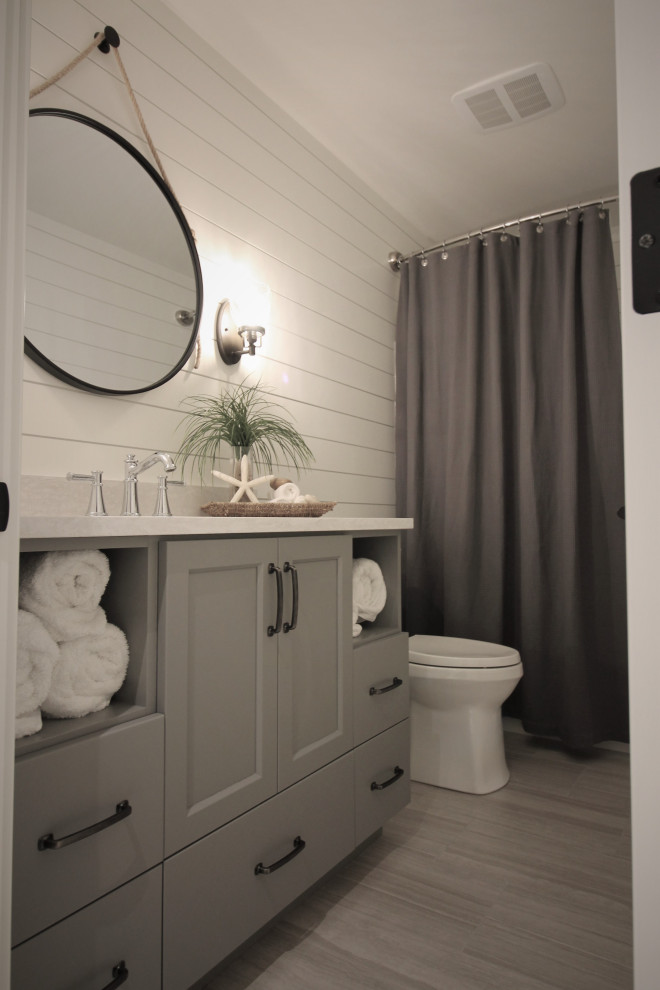 Medium sized rural family bathroom in Seattle with shaker cabinets, grey cabinets, an alcove bath, a shower/bath combination, a two-piece toilet, white tiles, white walls, porcelain flooring, a submerged sink, engineered stone worktops, grey floors, a shower curtain and white worktops.