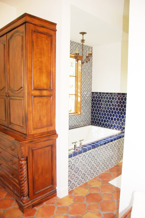 This is an example of a large mediterranean ensuite bathroom in New Orleans with a built-in bath, a two-piece toilet, blue walls, terracotta flooring and brown floors.