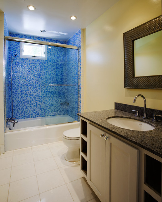 Klassisk inredning av ett mellanstort blå blått badrum för barn, med skåp i shakerstil, vita skåp, ett badkar i en alkov, en dusch/badkar-kombination, en toalettstol med hel cisternkåpa, blå kakel, mosaik, gula väggar, marmorgolv, ett undermonterad handfat, granitbänkskiva, vitt golv och dusch med skjutdörr