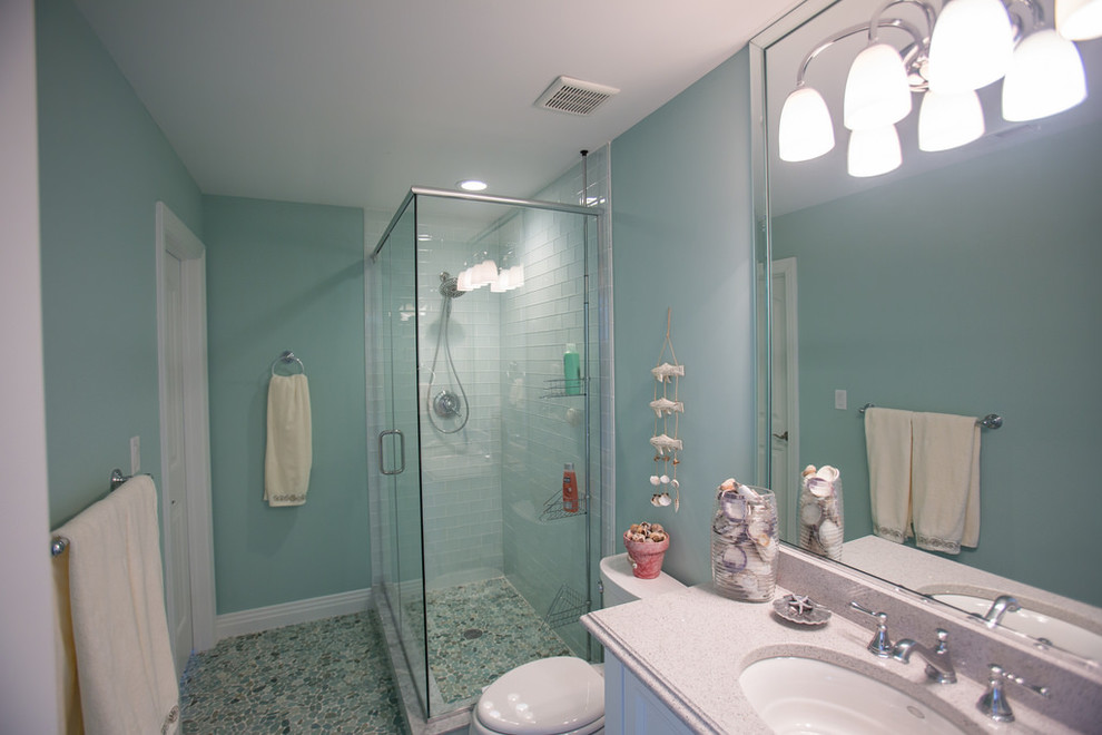 Bild på ett mellanstort maritimt badrum för barn, med vita skåp, en hörndusch, blå kakel, keramikplattor, blå väggar, mosaikgolv, ett undermonterad handfat, bänkskiva i kvarts, blått golv och dusch med gångjärnsdörr