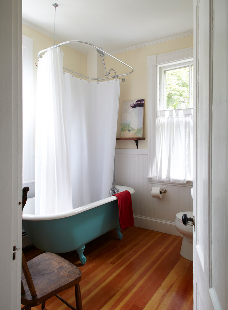 Immagine di una stanza da bagno stile marinaro con vasca con piedi a zampa di leone e pareti gialle