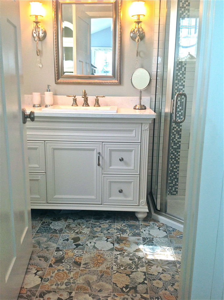 Large beach style master blue tile and ceramic tile ceramic tile corner shower photo in New York with raised-panel cabinets, white cabinets, white walls, a drop-in sink and solid surface countertops