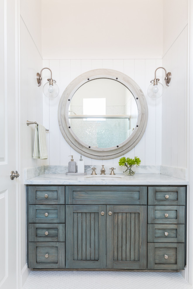 Beach style mosaic tile floor bathroom photo in Houston with blue cabinets