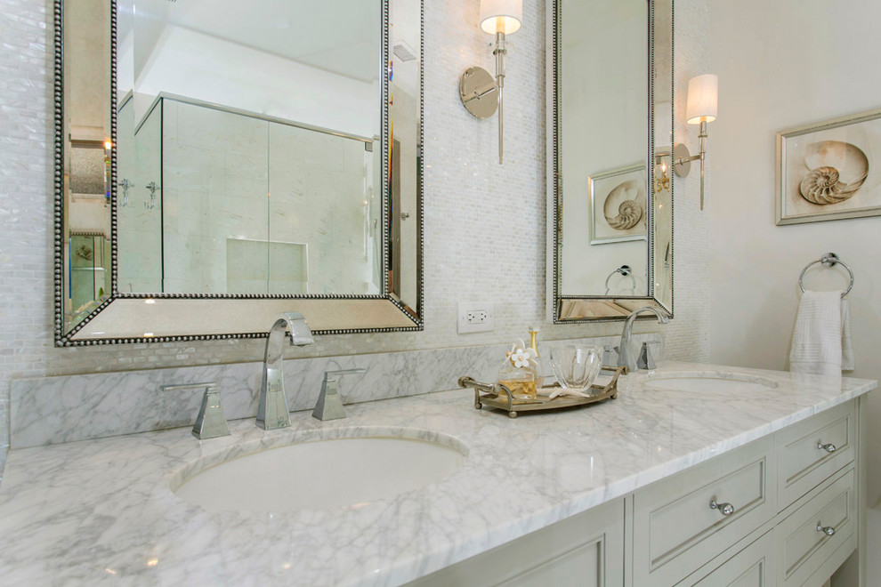 Inspiration for a classic ensuite bathroom in San Diego with recessed-panel cabinets, grey cabinets, a built-in shower, white tiles, glass sheet walls, grey walls, limestone flooring, a submerged sink, marble worktops and beige floors.