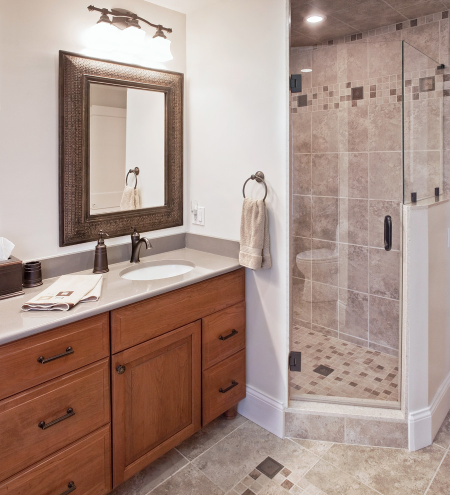 Klassisk inredning av ett mellanstort en-suite badrum, med ett undermonterad handfat, luckor med upphöjd panel, skåp i mörkt trä, bänkskiva i täljsten, en dusch i en alkov, en toalettstol med separat cisternkåpa, beige kakel, porslinskakel, beige väggar, mosaikgolv, grått golv och dusch med gångjärnsdörr