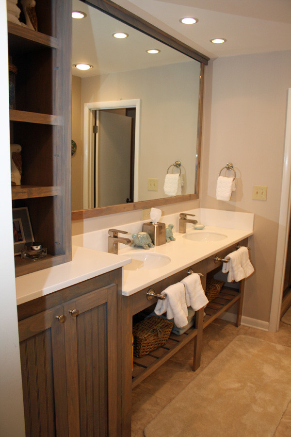 Example of a beach style bathroom design in Jacksonville with beaded inset cabinets, distressed cabinets and solid surface countertops