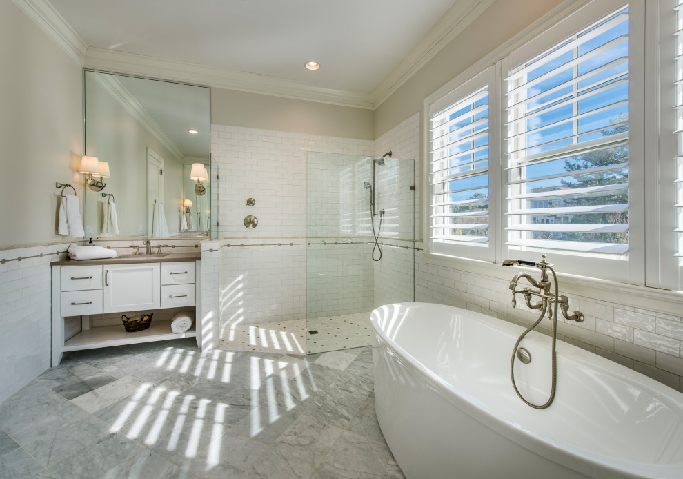 Стильный дизайн: большая главная ванная комната в морском стиле с фасадами с утопленной филенкой, белыми фасадами, отдельно стоящей ванной, угловым душем, белой плиткой, плиткой кабанчик, бежевыми стенами, мраморным полом, врезной раковиной, серым полом, открытым душем и коричневой столешницей - последний тренд