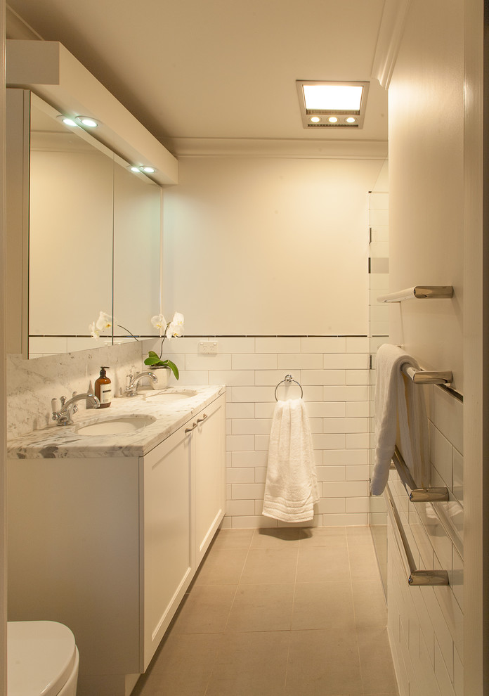 Immagine di una stanza da bagno classica con ante in stile shaker, ante bianche, piastrelle bianche, piastrelle diamantate, pareti bianche, lavabo sottopiano e top in marmo