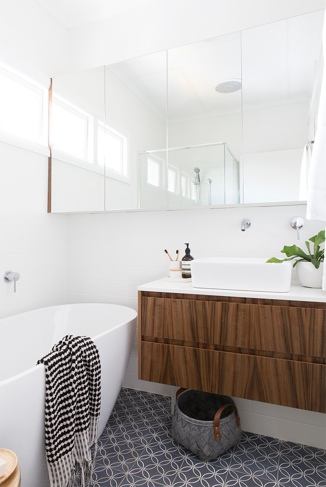 Inspiration for a nautical bathroom in Brisbane with flat-panel cabinets, dark wood cabinets, a freestanding bath, white walls, a vessel sink and grey floors.