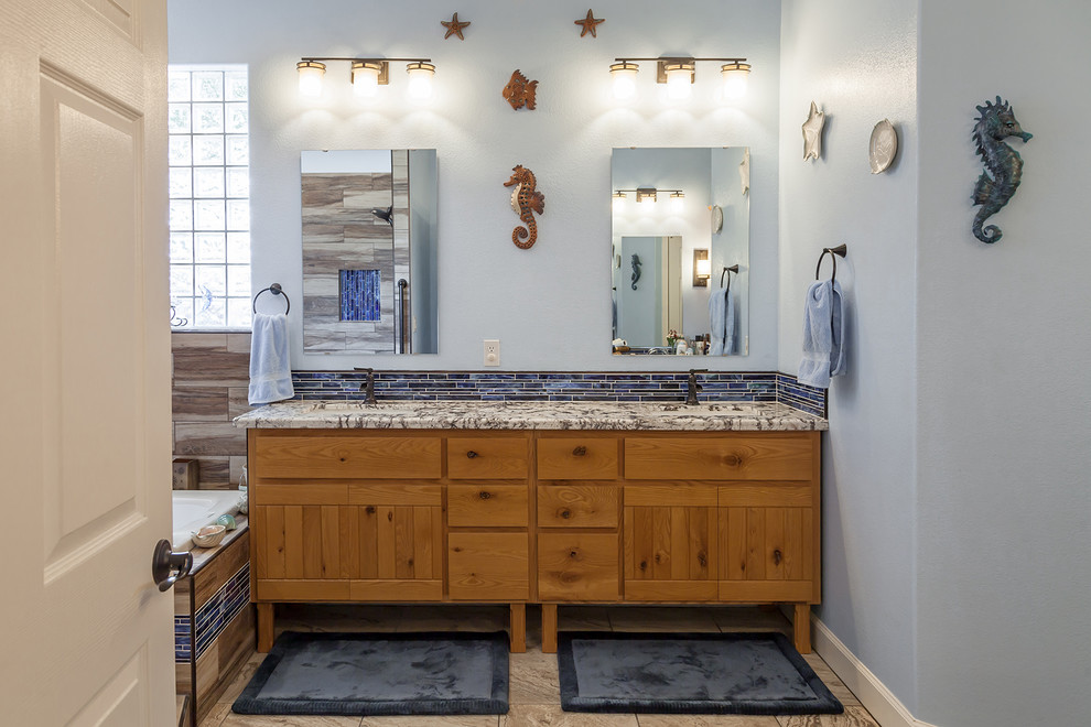 This is an example of a large nautical ensuite bathroom in Phoenix with freestanding cabinets, medium wood cabinets, a built-in bath, a double shower, a one-piece toilet, multi-coloured tiles, ceramic tiles, brown walls, ceramic flooring, a submerged sink, granite worktops, beige floors and an open shower.