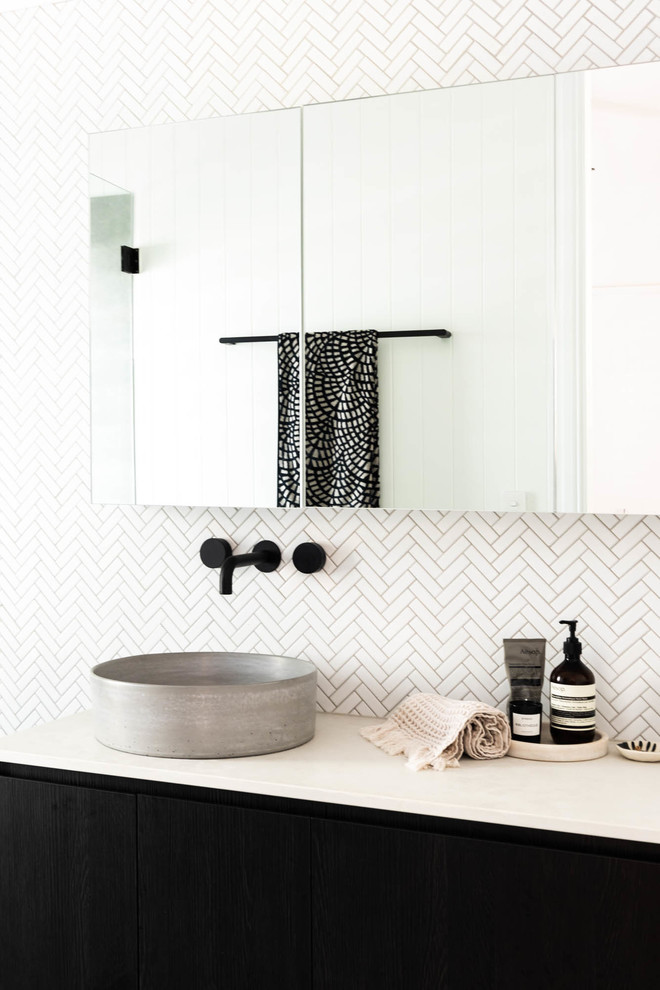Immagine di una stanza da bagno stile marino con ante lisce, ante nere, piastrelle bianche, piastrelle a mosaico, pareti bianche, lavabo a bacinella e top bianco