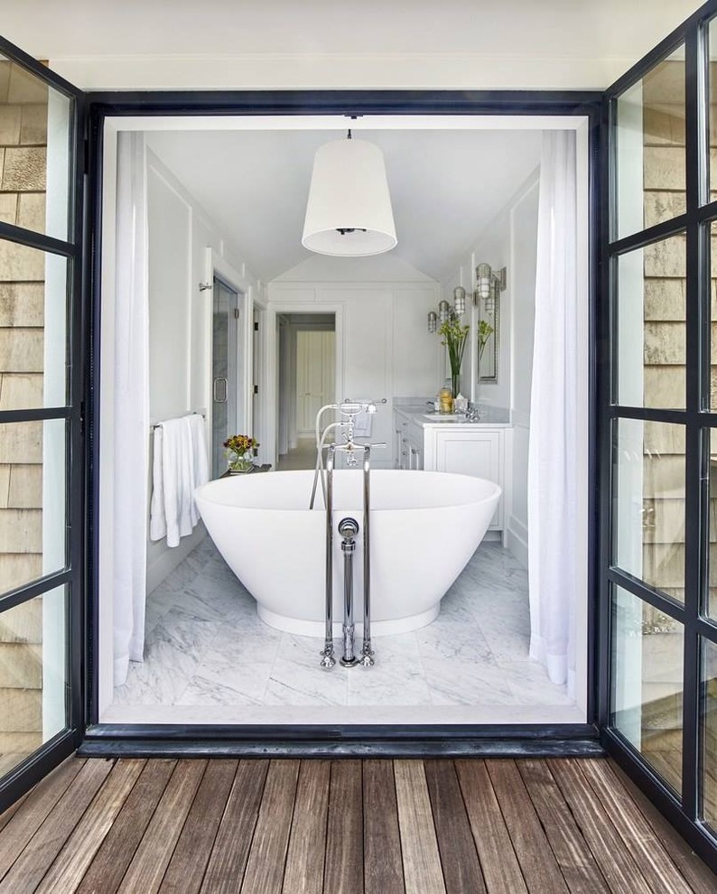 Bild på ett mellanstort maritimt grå grått en-suite badrum, med vita skåp, ett fristående badkar, vita väggar, ett undermonterad handfat, vitt golv, dusch med gångjärnsdörr, en dusch i en alkov, marmorgolv och marmorbänkskiva