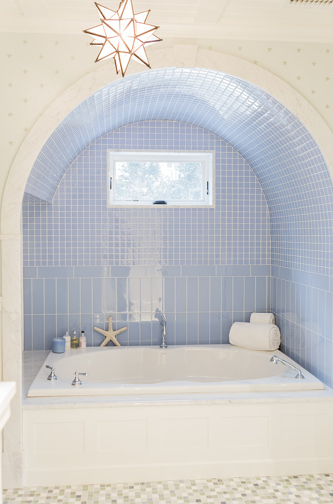 На фото: главная ванная комната в морском стиле с ванной в нише, синей плиткой и окном с