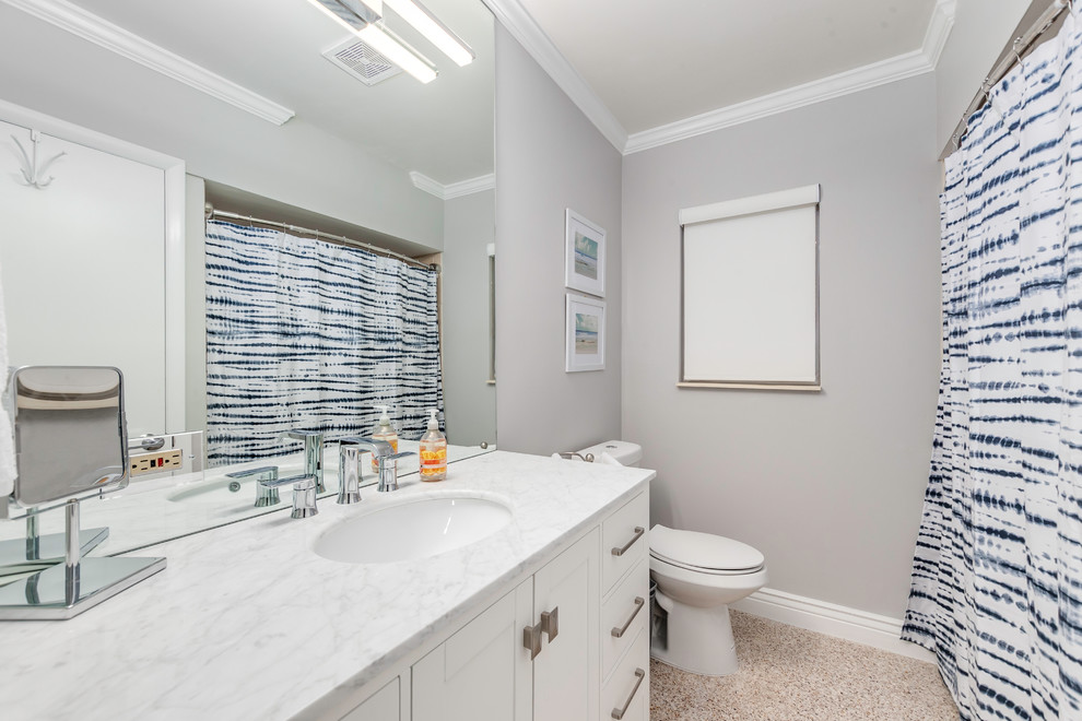 Idée de décoration pour une salle de bain marine avec un placard à porte shaker, des portes de placard blanches, WC séparés, un mur gris, un lavabo encastré, un sol beige, une cabine de douche avec un rideau et un plan de toilette blanc.