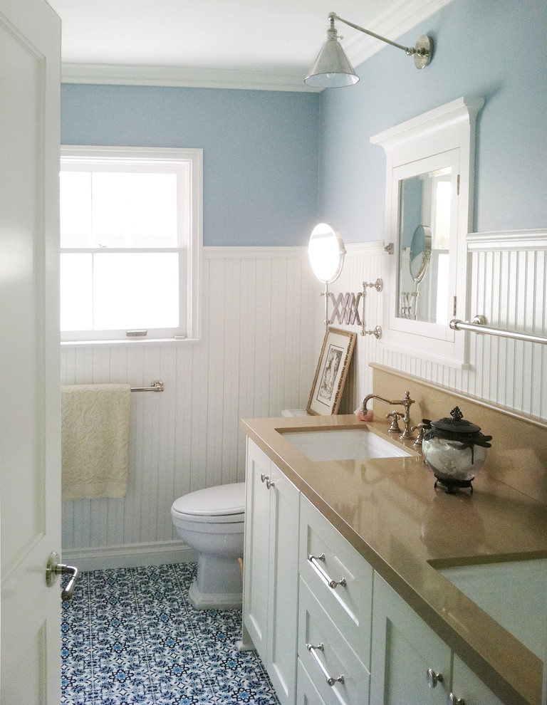 Bathroom - mid-sized coastal blue tile blue floor and ceramic tile bathroom idea in Austin with an undermount sink, shaker cabinets, white cabinets, a one-piece toilet, blue walls, quartz countertops and brown countertops