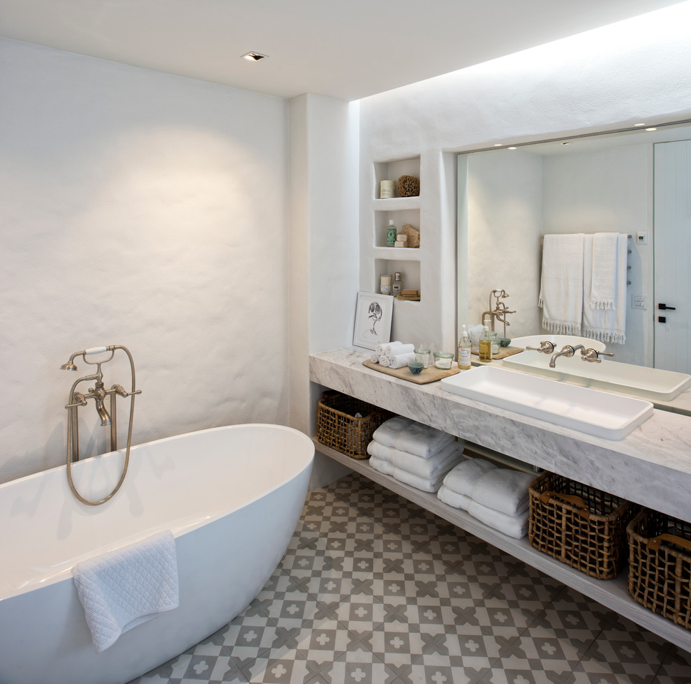Photo of a coastal bathroom in Sydney with open cabinets, white cabinets, a freestanding bath, grey tiles, white tiles, white walls and a built-in sink.