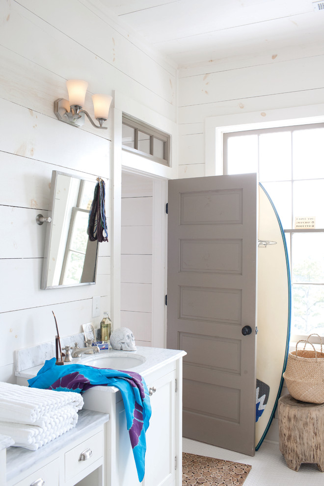Modelo de cuarto de baño marinero con lavabo sobreencimera, armarios estilo shaker, puertas de armario blancas y paredes blancas